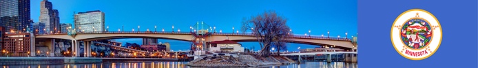 A bridge over an expanse of water and some buildings with the state flag of Minnesota.