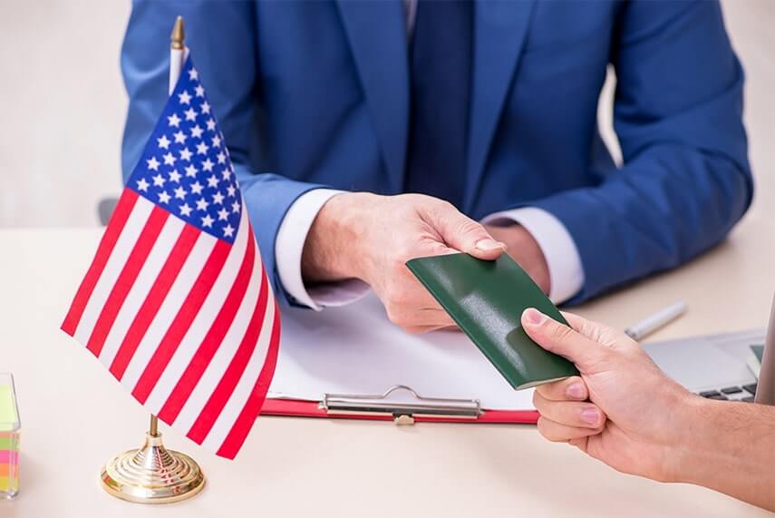 Man in suit handing over an ID document with an American flag on the desk.