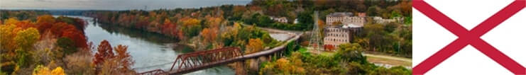 Lush greenery and a bridge over a lake with the state flag of Alabama.